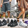 A Japanese man and woman wearing Nike Air More Uptempo sandals in different styles and colors, showcasing fashionable ways to wear the sandals. The background is a modern urban setting.