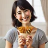 A happy person holding a pack of thin, stick-like snacks resembling pretzel sticks, with a joyful expression. The background is simple, focusing on their happiness after obtaining the snack. The person is Japanese, casually dressed, and smiling in a light, positive environment.